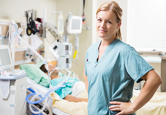 Sairaanhoitaja seisoo etualalla hoitohuoneessa